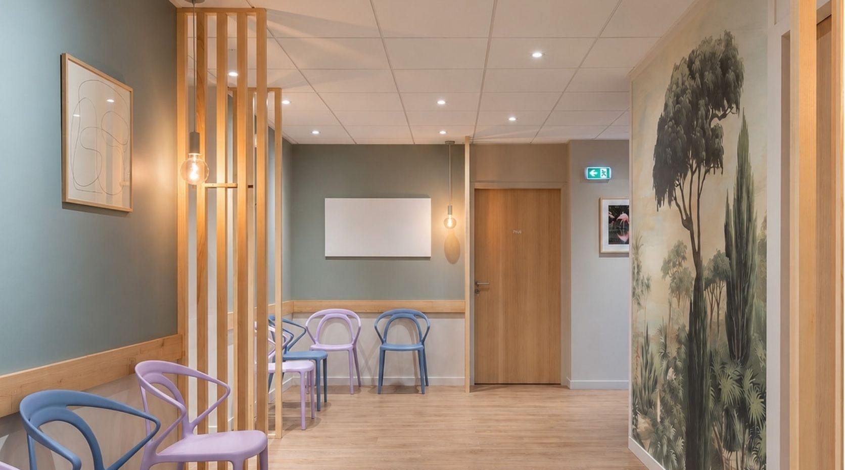 A waiting area of an animal hospital with light wood flooring, chairs, and a large wall depicting a forest scene.